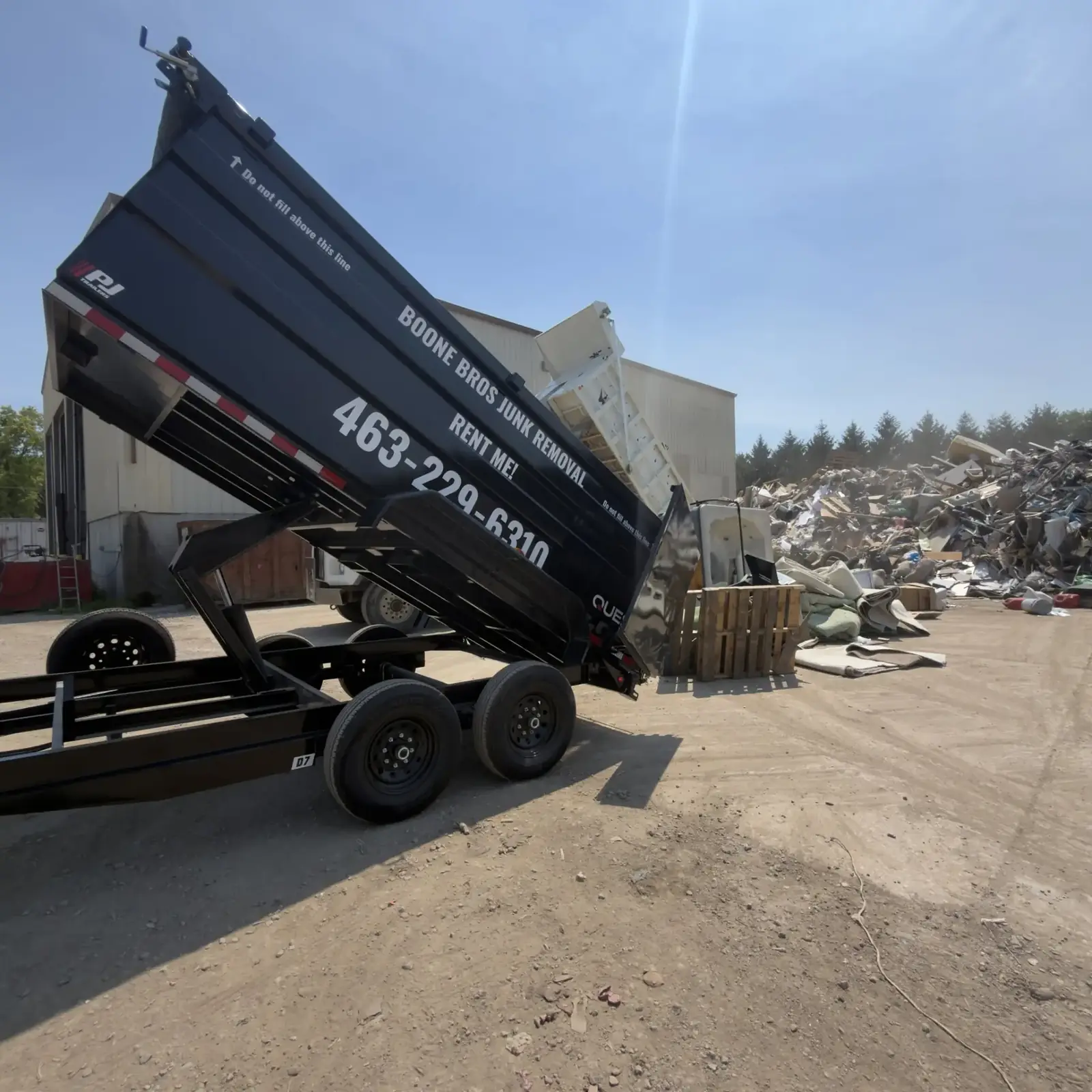 Boone Bros black dump trailer tipping a full load at the transfer station