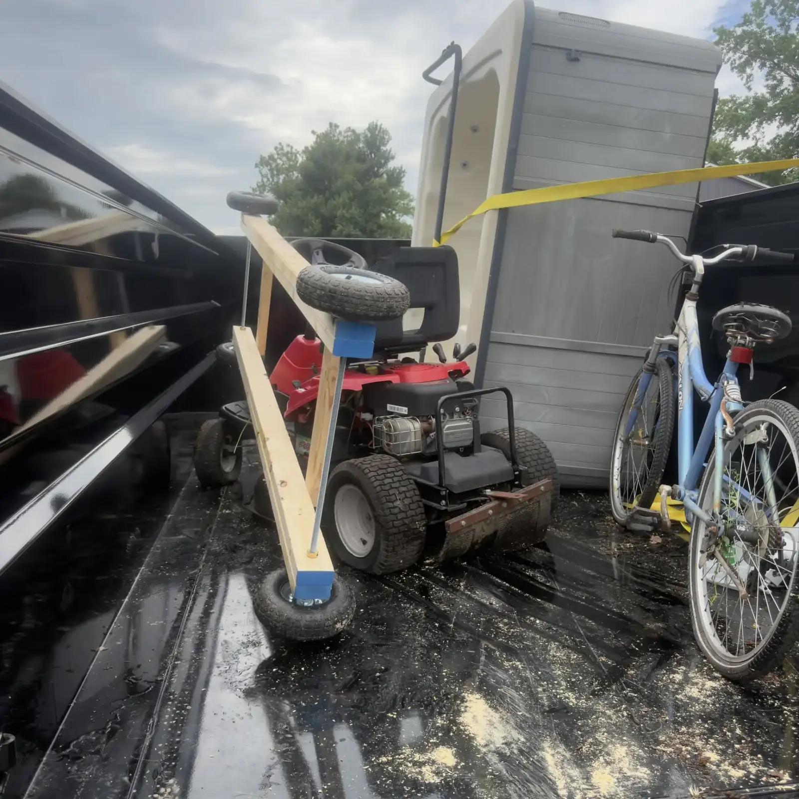 Boone Bros dump trailer loaded with a mower, bike and household junk